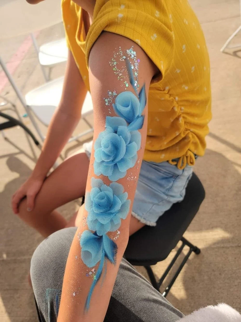 Blue floral body art painted on an arm