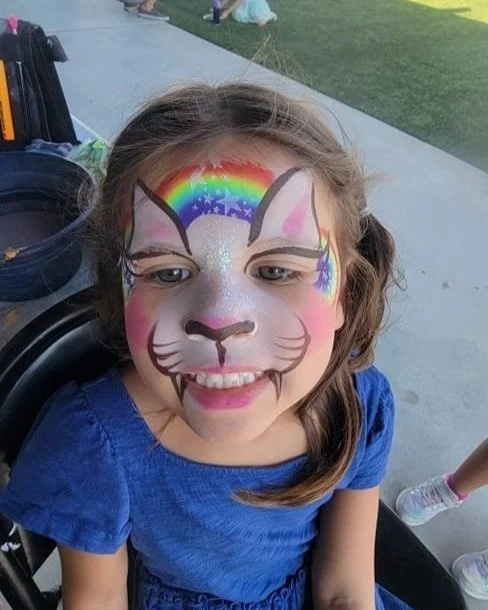 Smiling child with rainbow cat face painting