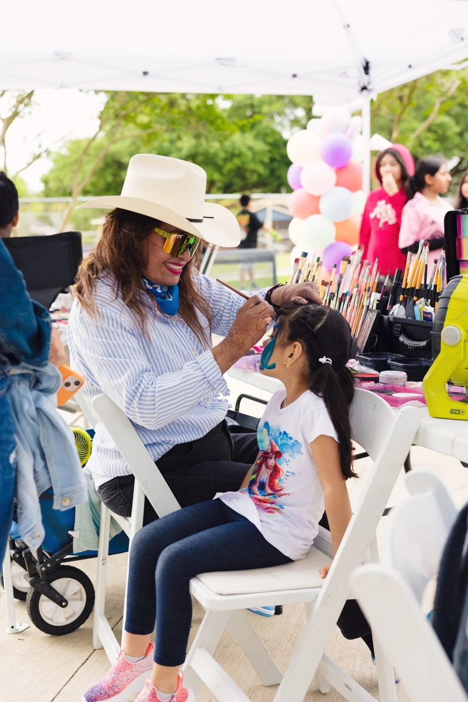 Paty DeLeon painting a child's face at an outdoor event